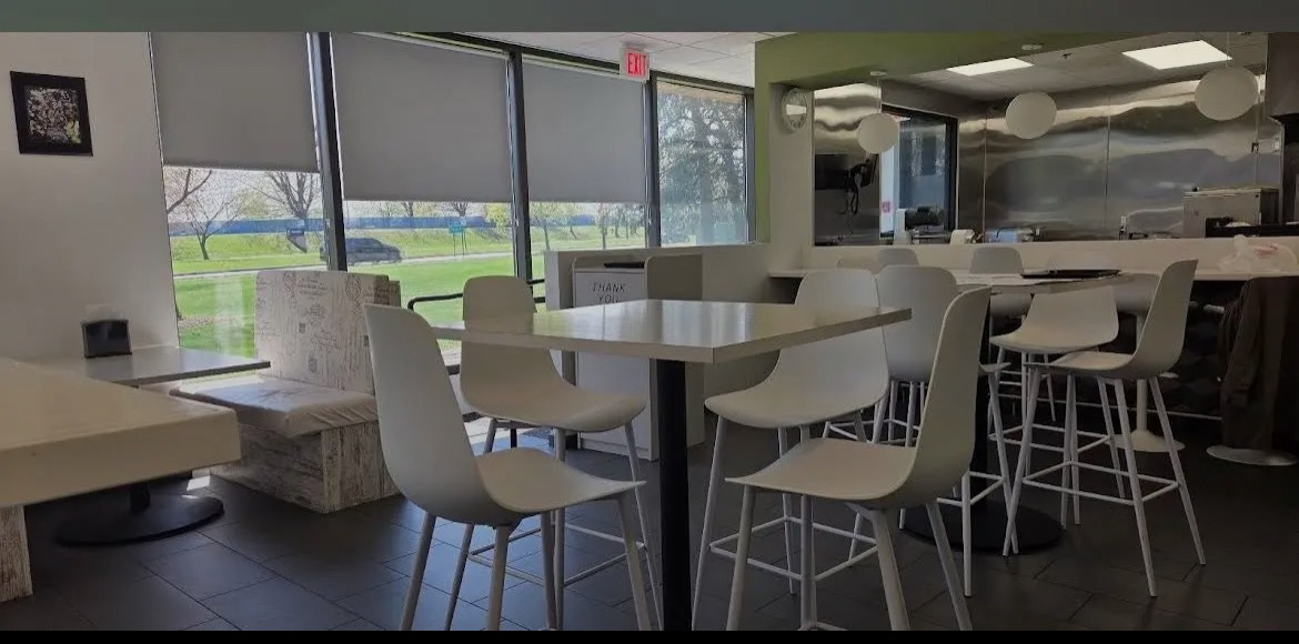 Bright dining room inside Shawarma Shop with white chairs and open kitchen